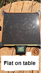 10 Watt Solar Panel with built-in Charge Controller outside in sunshine flat on a table.